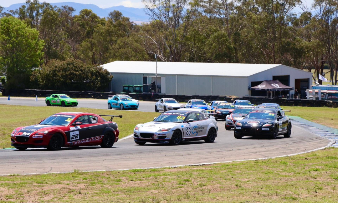 Mazda RX‑8 Cup field battling through a corner during a race at an Australian motorsport circuit.