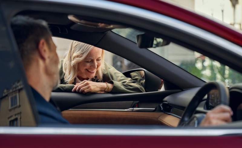 A couple in a car exchanging glances, carefree with their Mazda Assured car loan.