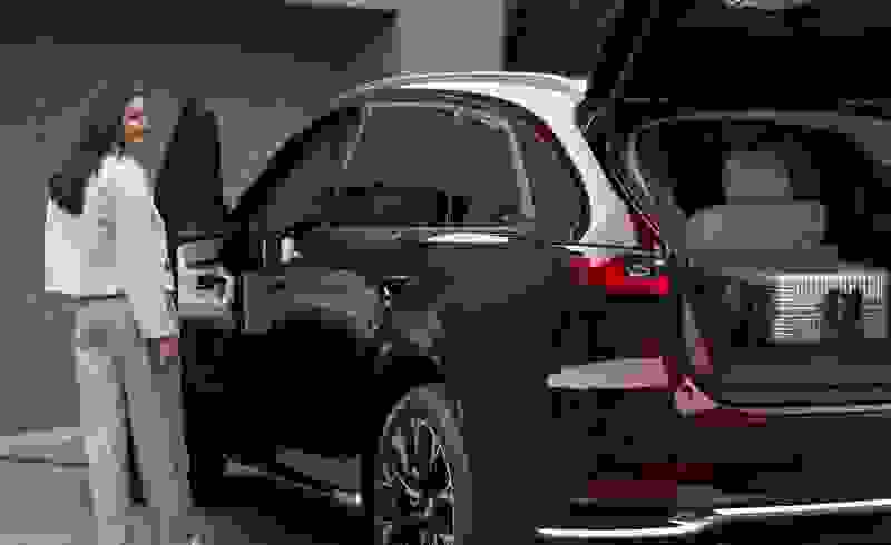 A woman is preparing to leave home on a road trip in the CX 90 purchased with Mazda Finance.