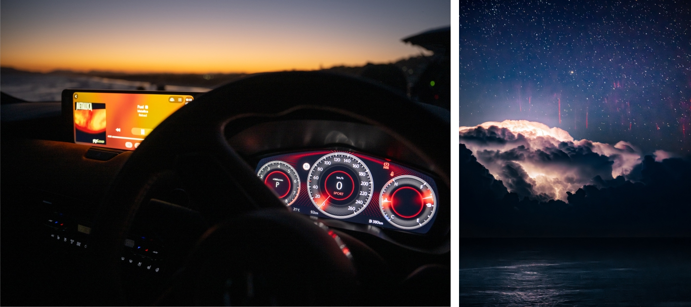 Interior view from the driver’s seat of a Mazda CX‑80 at dusk, with illuminated digital gauges and a storm‑lit sky visible beyond.