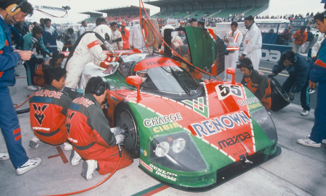 Mazda 787B No.55 undergoing a pit stop during the 1991 Le Mans 24 Hours, with crew servicing the iconic orange and green race car