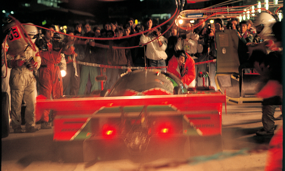 Mazda 787B No.55 during a night pit stop at the 1991 Le Mans 24 Hours, team servicing the rotary-powered race car under lights