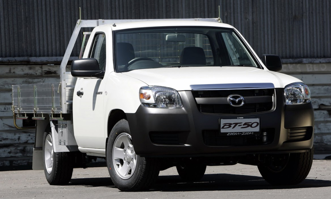 First-generation white Mazda BT-50 single-cab chassis with a tray, a work-spec ute