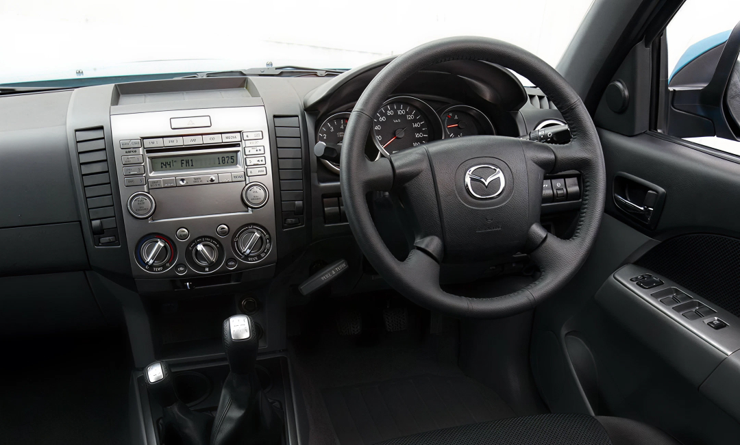 Interior of an early Mazda BT-50 dual-cab showing the dashboard and steering wheel