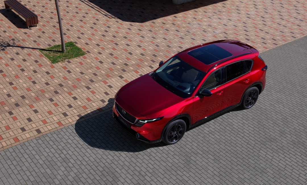 2026 Mazda CX-5 in Soul Red Crystal parked on patterned brick pavement with black alloy wheels and sunroof—stylish SUV design in urban outdoor setting.
