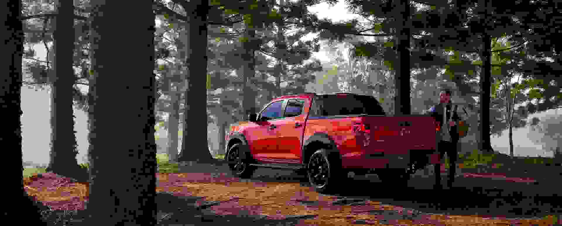 All-New 2025 Red Earth Mazda BT-50 ute parked in a tranquil forest with tall trees, showcasing rugged design and readiness for outdoor adventure.