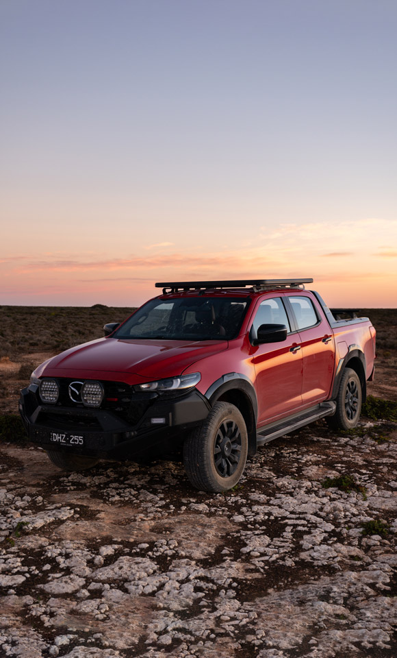 Mazda BT-50 parked on the rocks with the sunset background