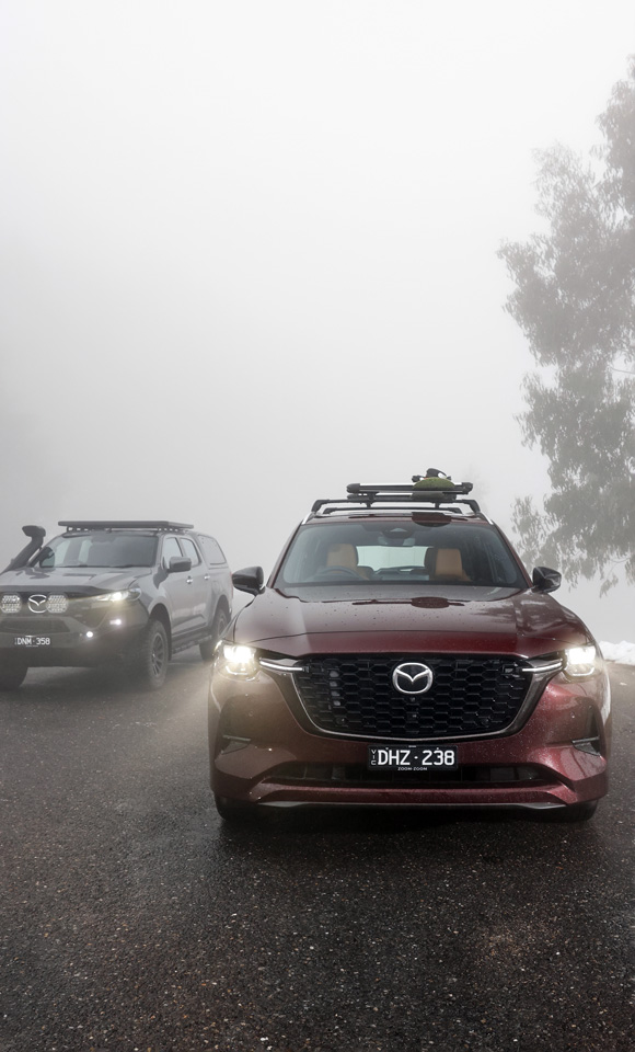 Mazda CX-80 and Mazda BT-50 parked on road with fog in the background