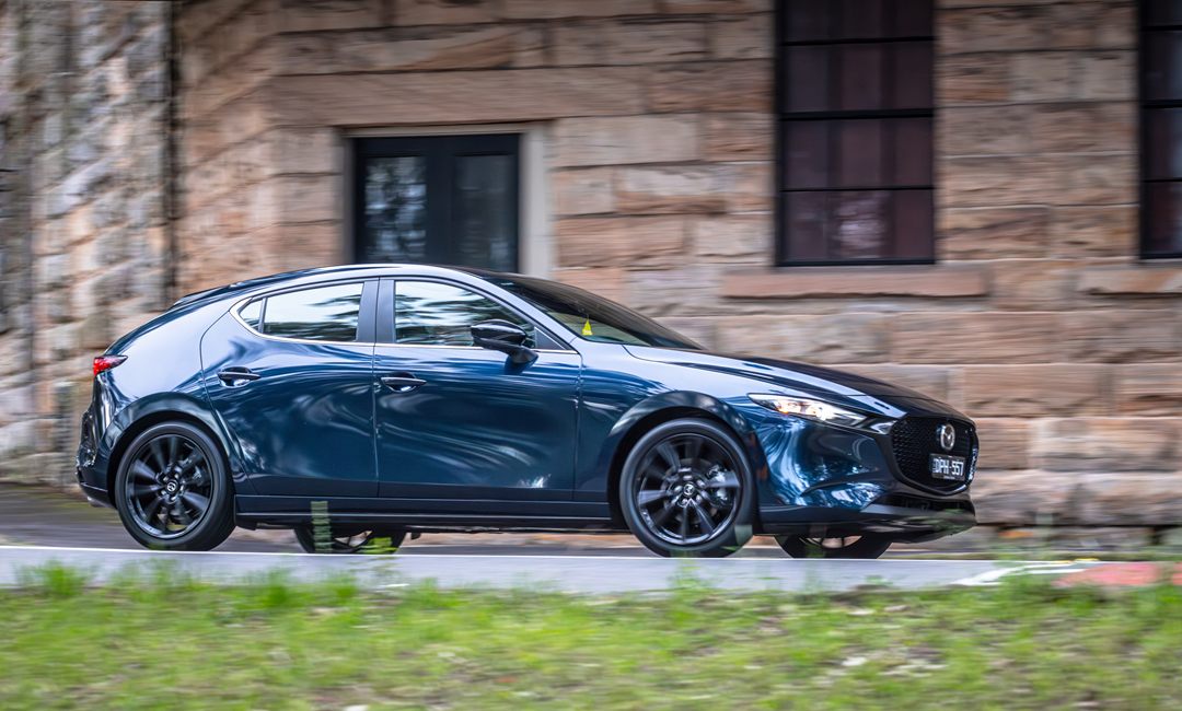 Side profile of a blue Mazda3 hatchback with black alloy wheels