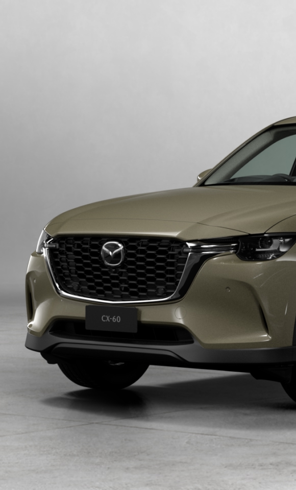 Front-left view of green Mazda CX-60 SUV parked on concrete with grey background, showcasing signature grille, headlights, and alloy wheels.