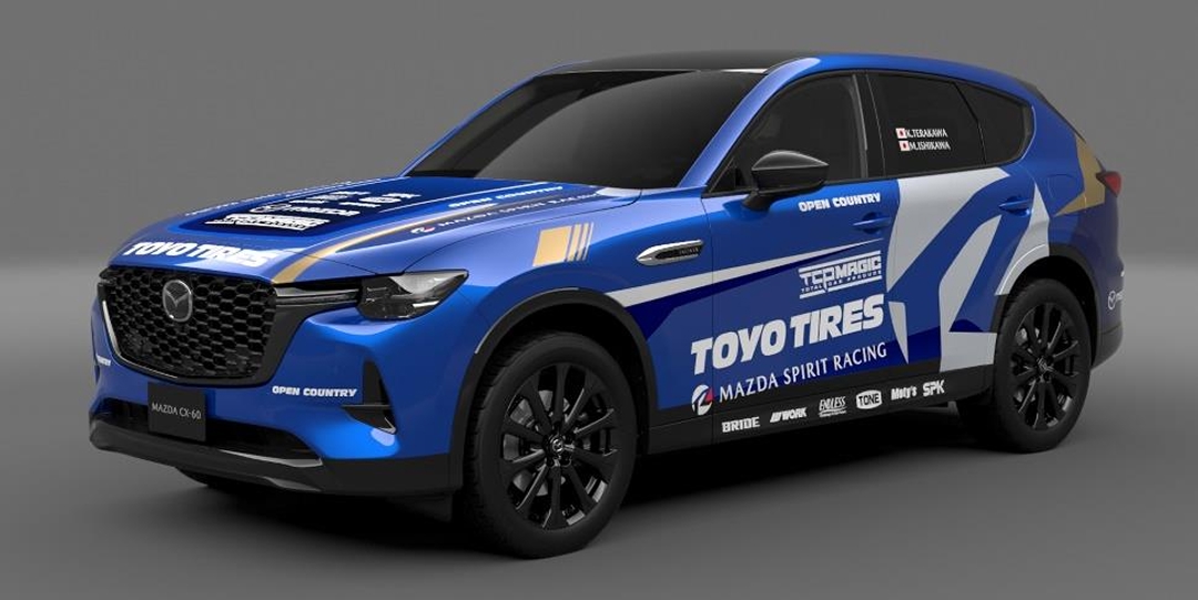 Customized Mazda CX-60 SUV in full racing livery featuring Toyo Tires, Mazda Spirit Racing, and multiple sponsor logos. Bold blue design with white and gold accents highlights motorsport branding.