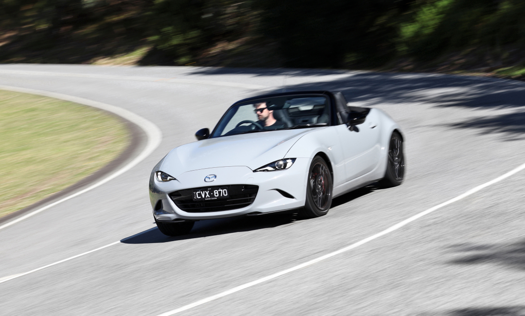 Grey Mazda MX-5 convertible sports car driving on a winding mountain road in Victoria, Australia, highlighting agile performance and sleek design.