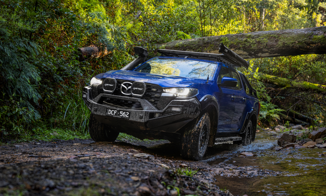 Blue Mazda BT-50 4x4 ute driving through a rocky creek in Toolangi State Forest, Victoria, Australia, showcasing rugged off-road capability and adventure-ready design.