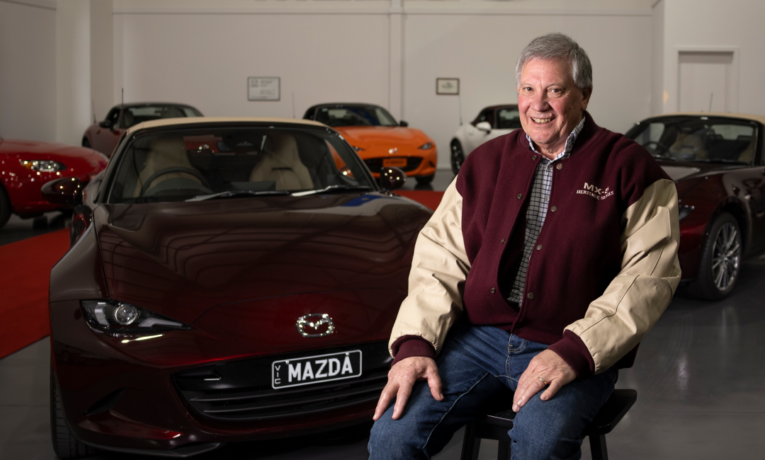 Mazda MX-5 35th Anniversary Edition in deep burgundy showcased in a premium indoor collection, with multiple generations of MX-5 roadsters displayed in the background, celebrating Australia&rsquo;s greatest MX-5 collection.